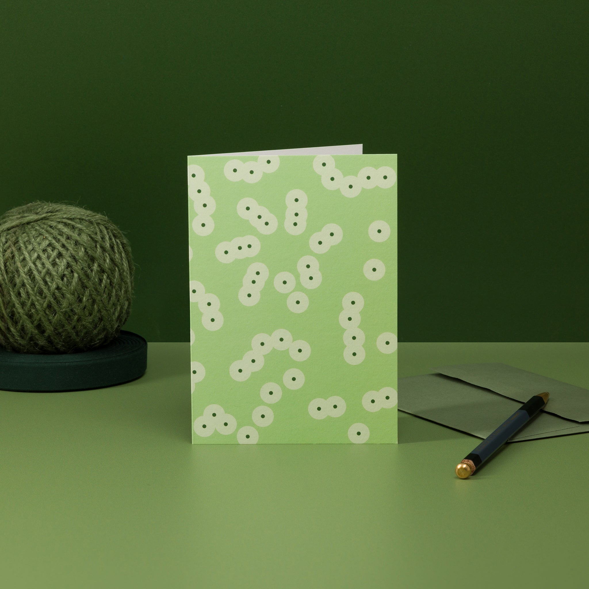 Spawn (green) greeting card, with a pattern of clustering circles resembling frog spawn. Shown with matching sage green envelope.