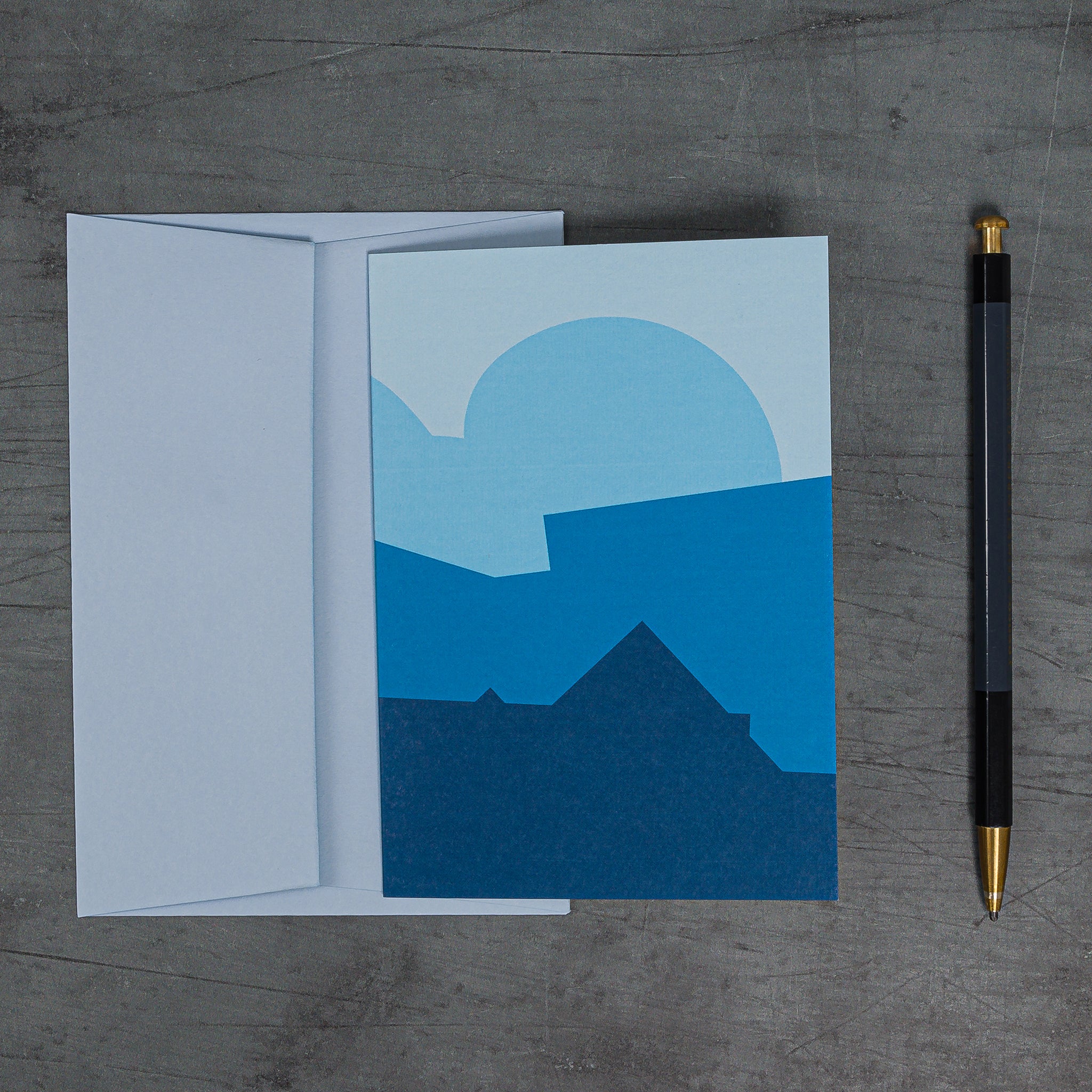 Stack (blue) greeting card and matching pale blue envelope. Design: a stack of geometric angles and curves, redolent of both landcape and architecture