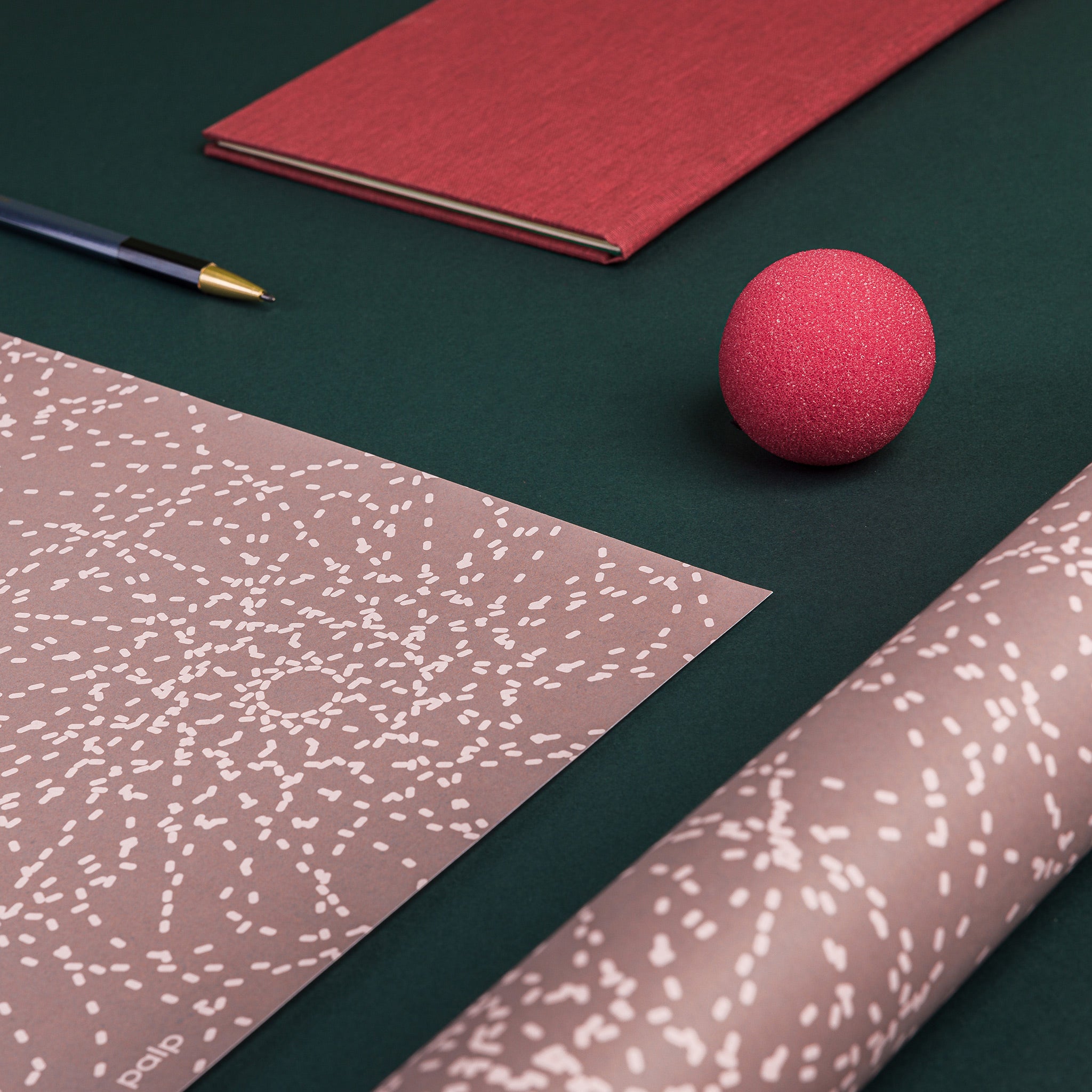 Partial view of two sheets of Synapse gift wrap - one flat, one folded. Pattern: radiating circles with dotted lines, inspired by neurological networks
